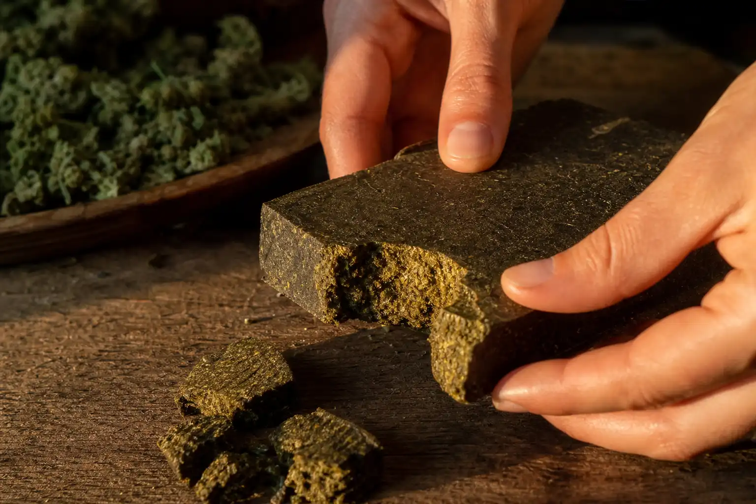 Des mains préparent quelque chose, autour de cbd pressée froid, près d'une table en bois.