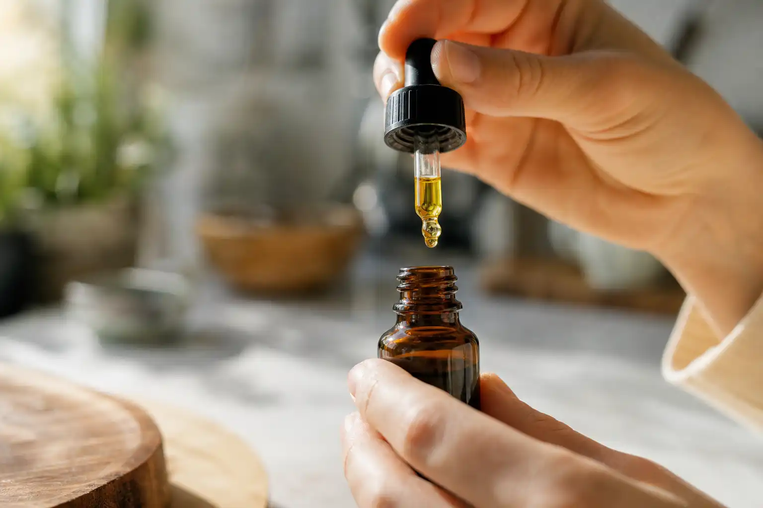 Des mains disposent un objet, autour de liquide cbd, dans une cuisine.